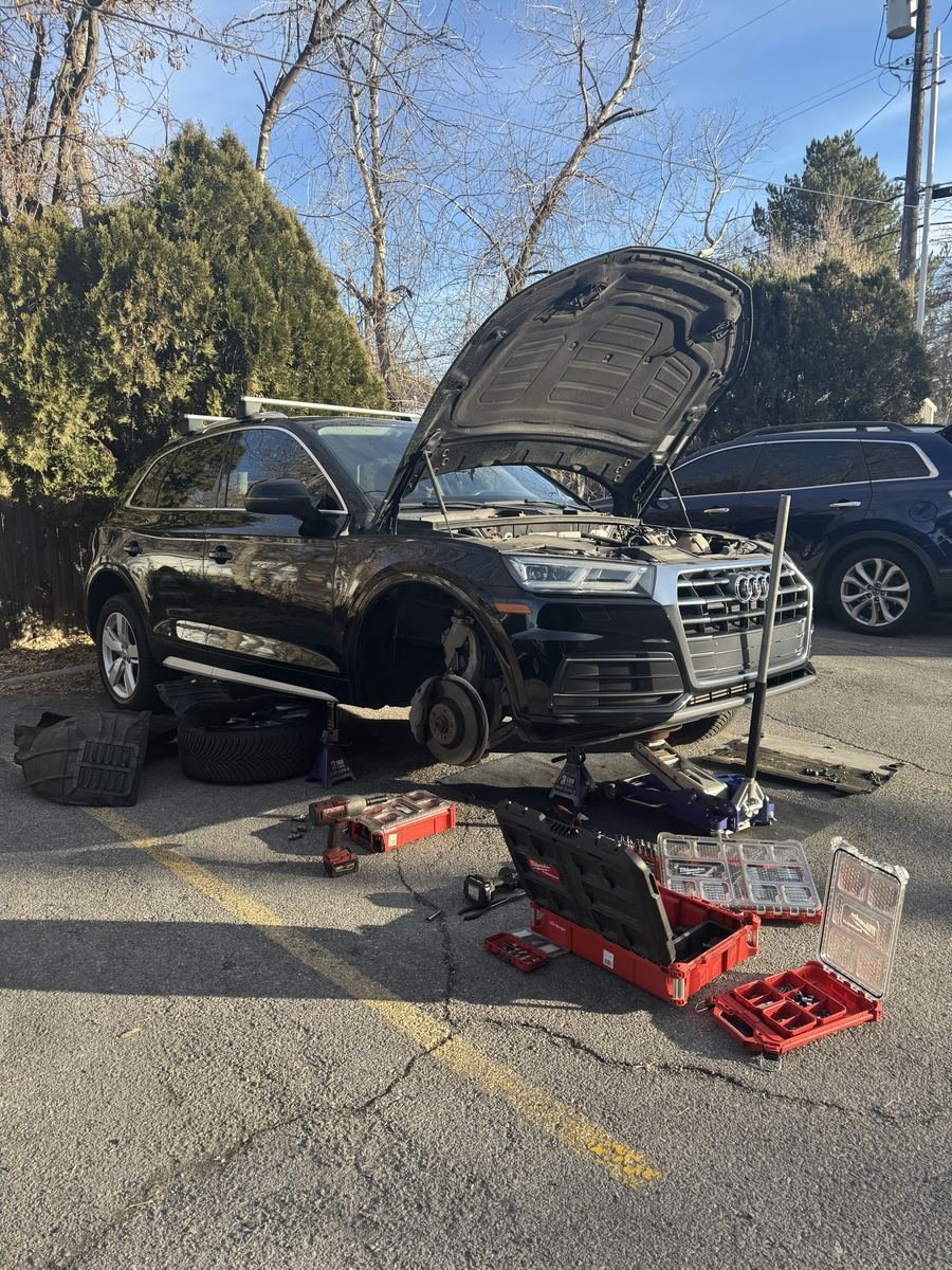 Audi Q5 on a jack with a front wheel off and tool cases laid out