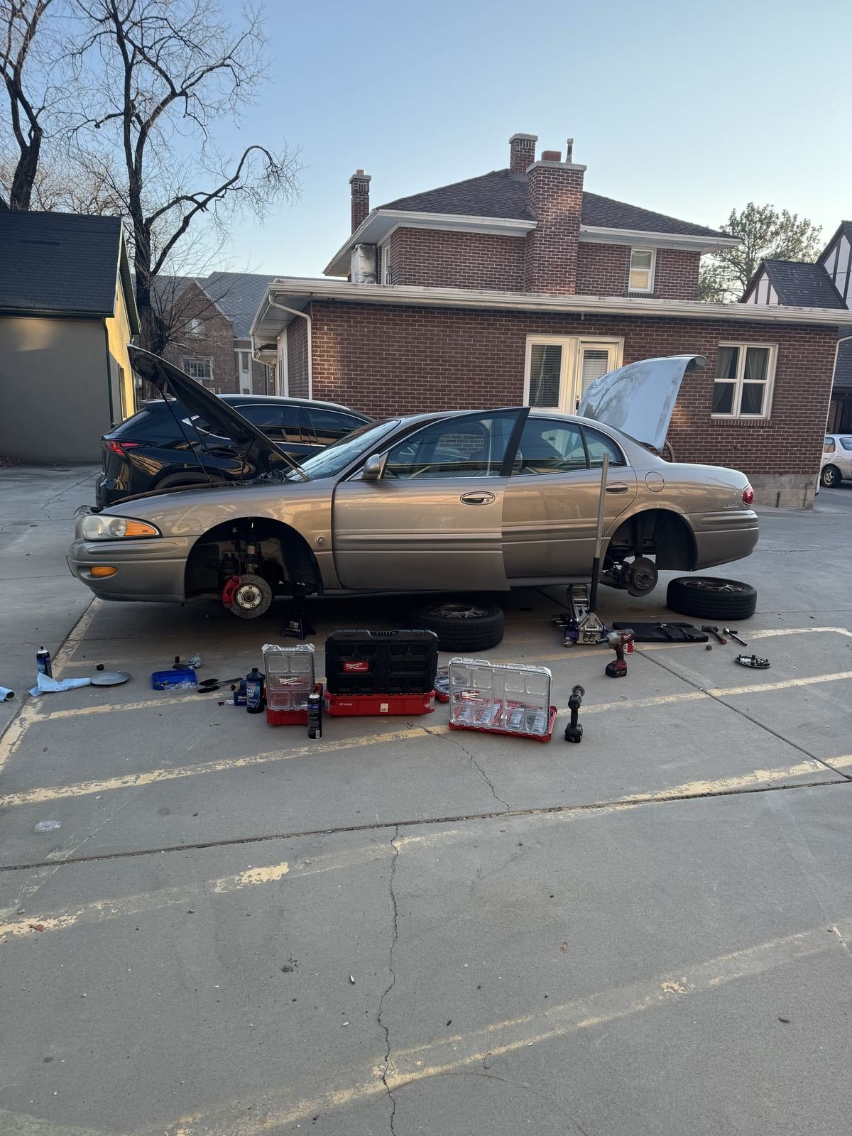 Buick sedan on jack stands with both front wheels off in a parking lot