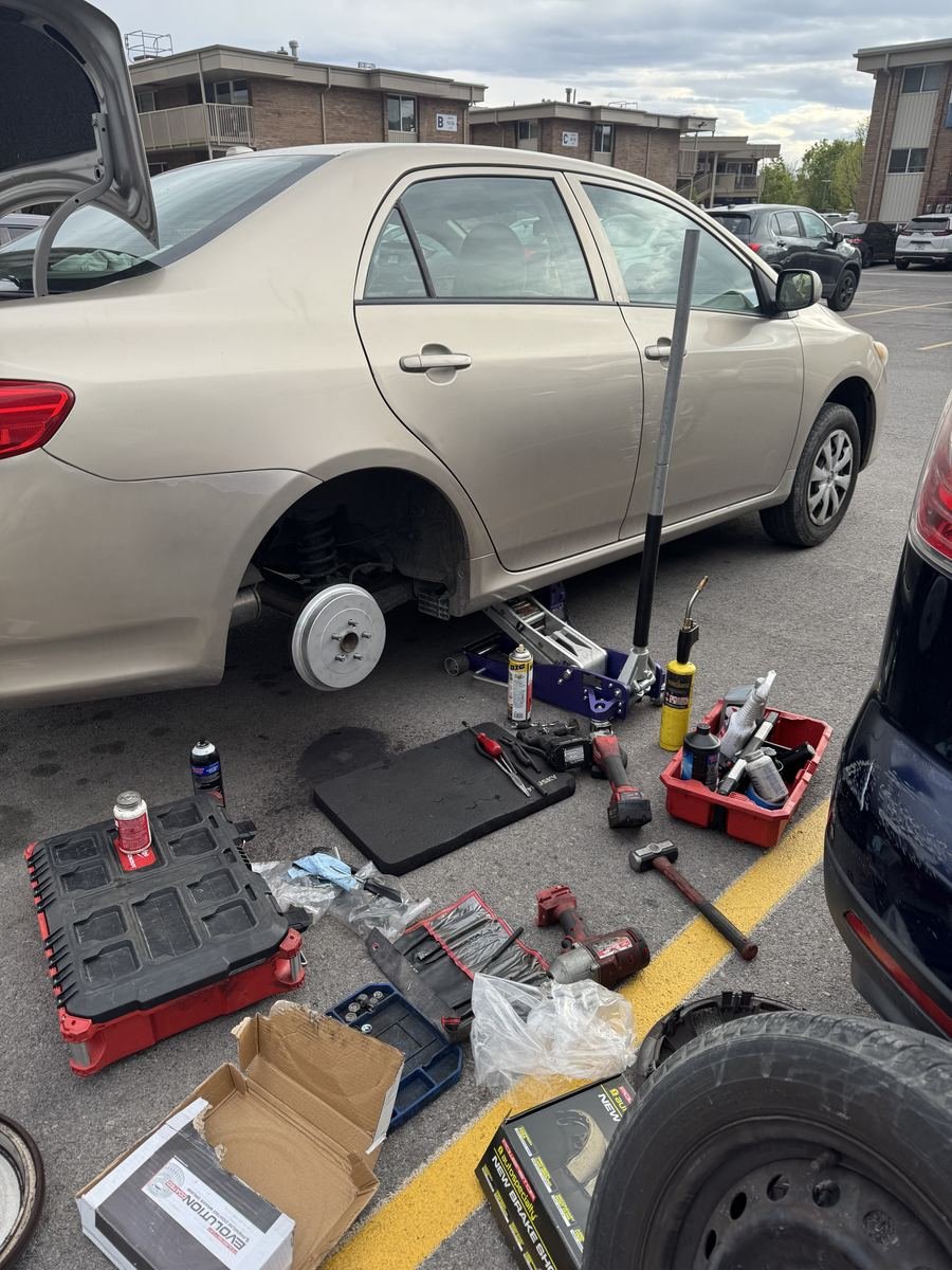 Toyota Corolla with a rear wheel off and tools around it