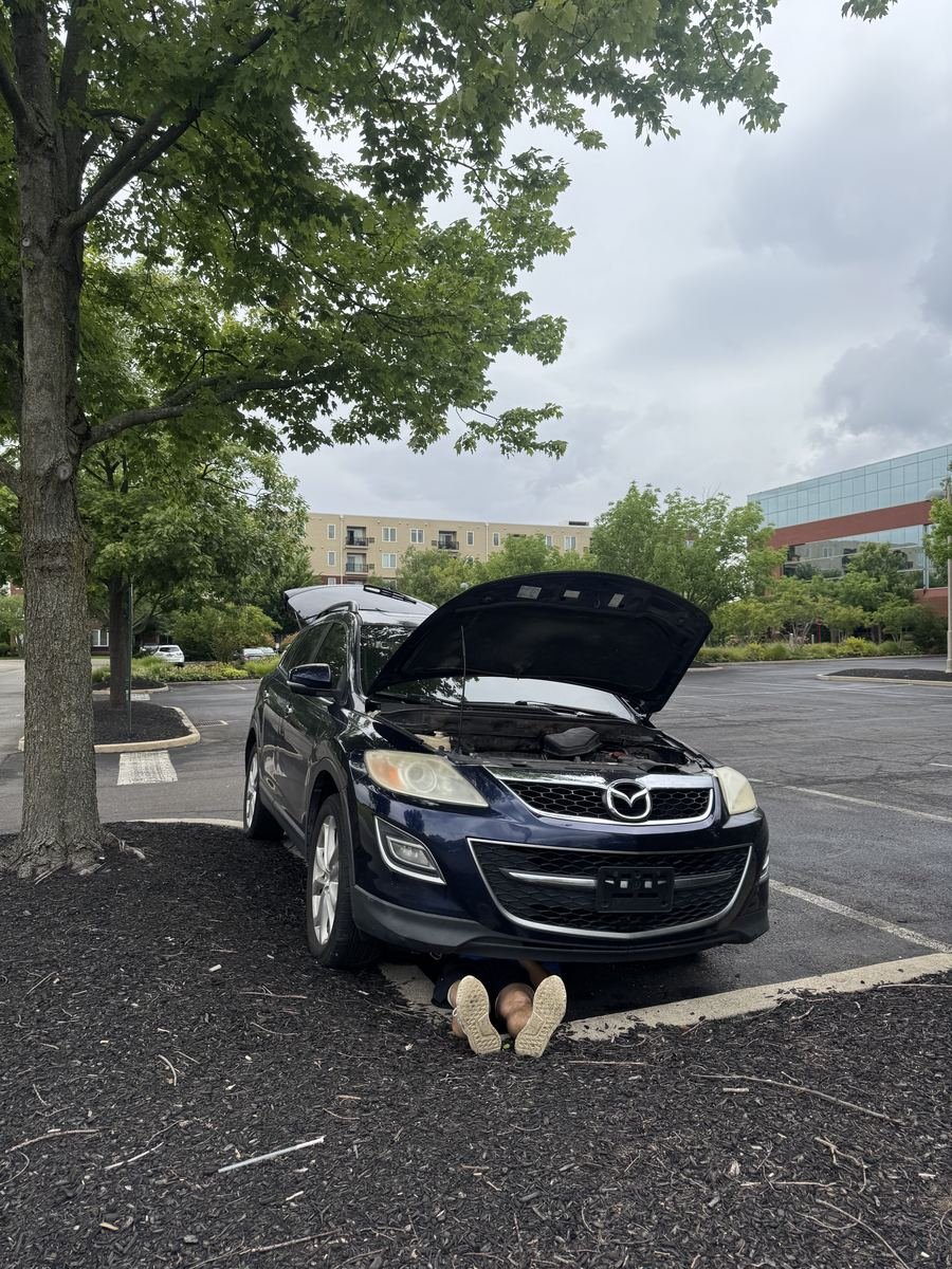 Mazda CX-9 with the hood up, Emilio underneath the car