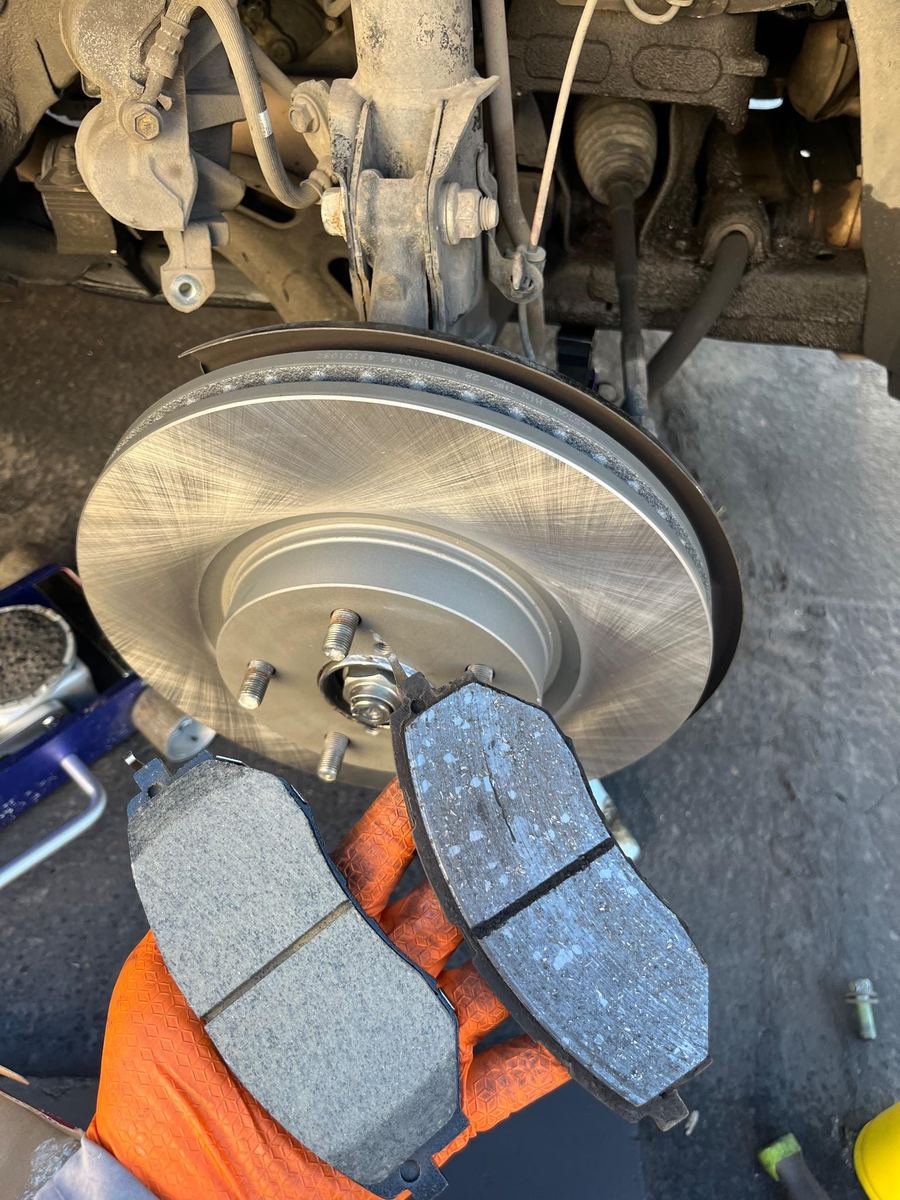New brake pads held up next to a fresh rotor