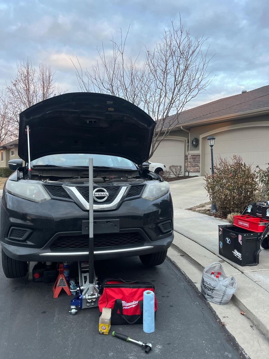 Nissan Rogue on a jack in a driveway with the hood up